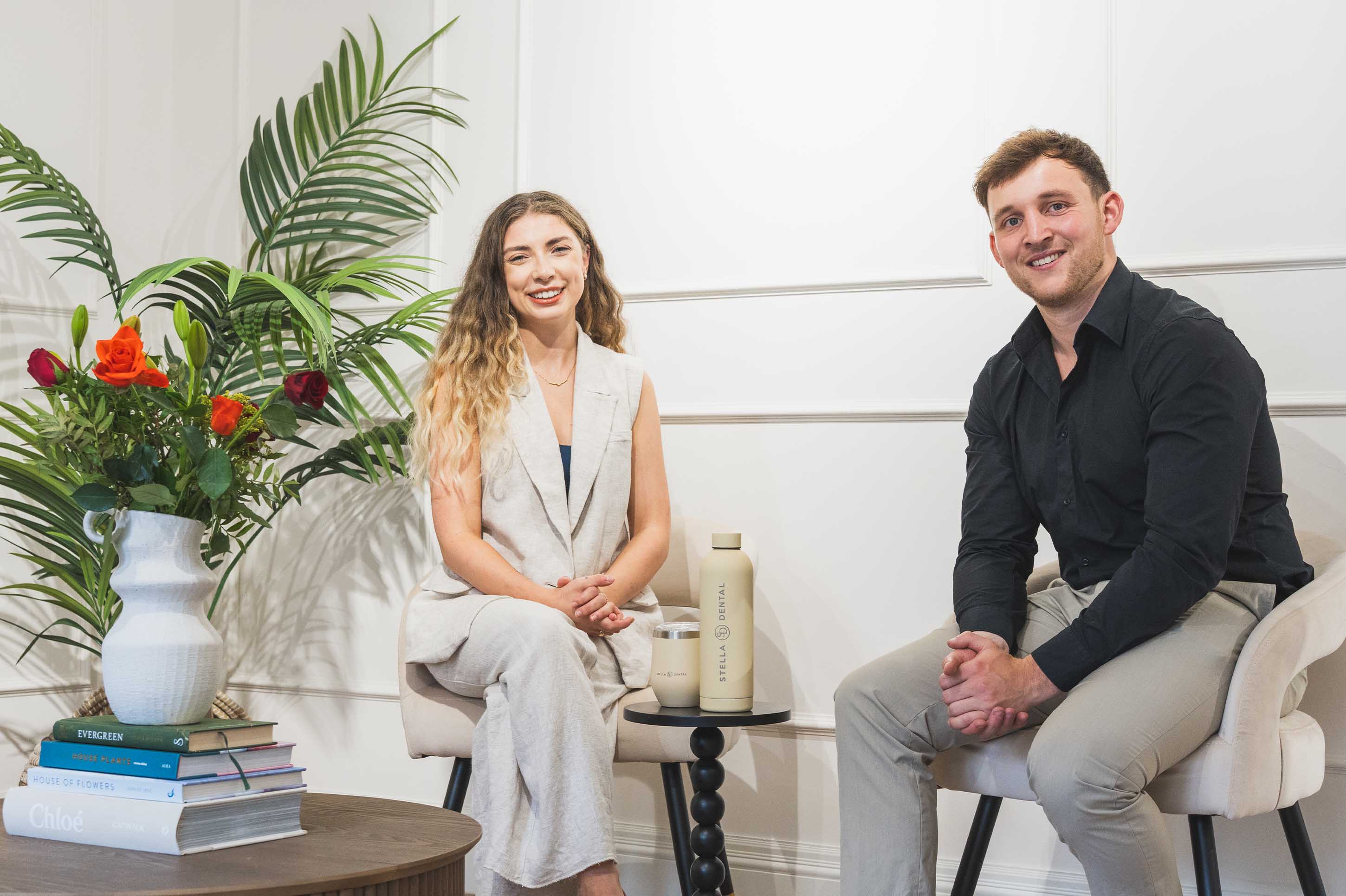 Two people are sitting in the modern interior of Stella Dental with decor elements.