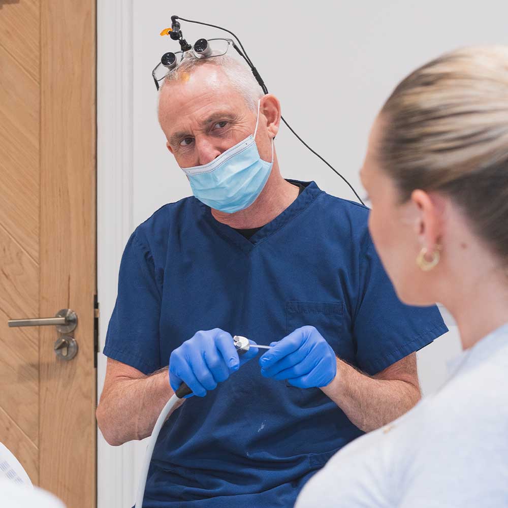Dentist in blue scrubs is interacting with another person.