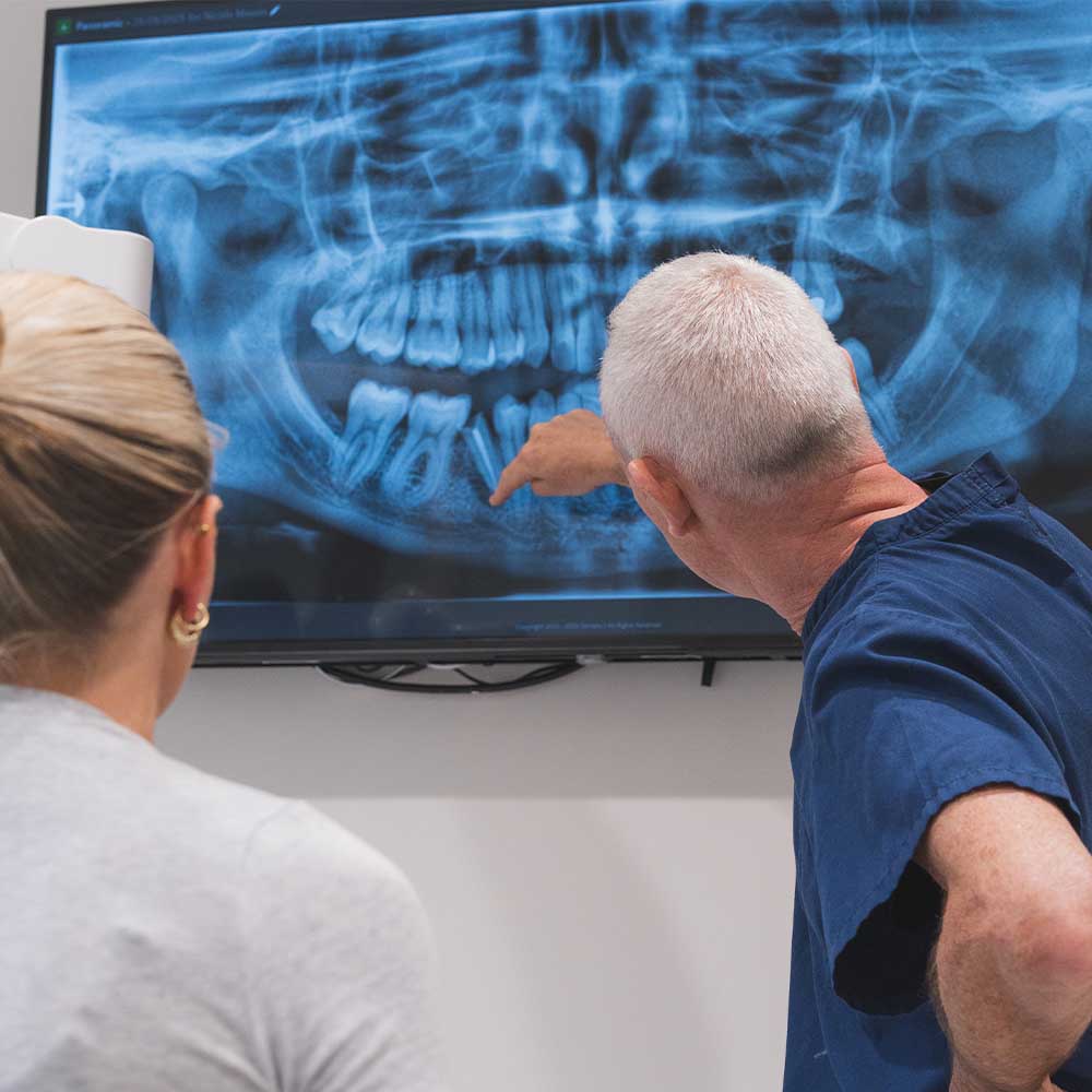Two people examining a dental X-ray on a screen.