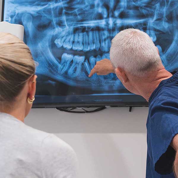 Two people examining a dental X-ray on a screen.