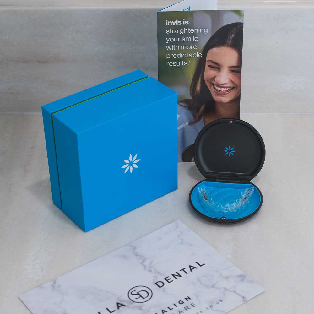 Invisalign aligner case with blue aligners, blue box, and promotional material on a marble surface.