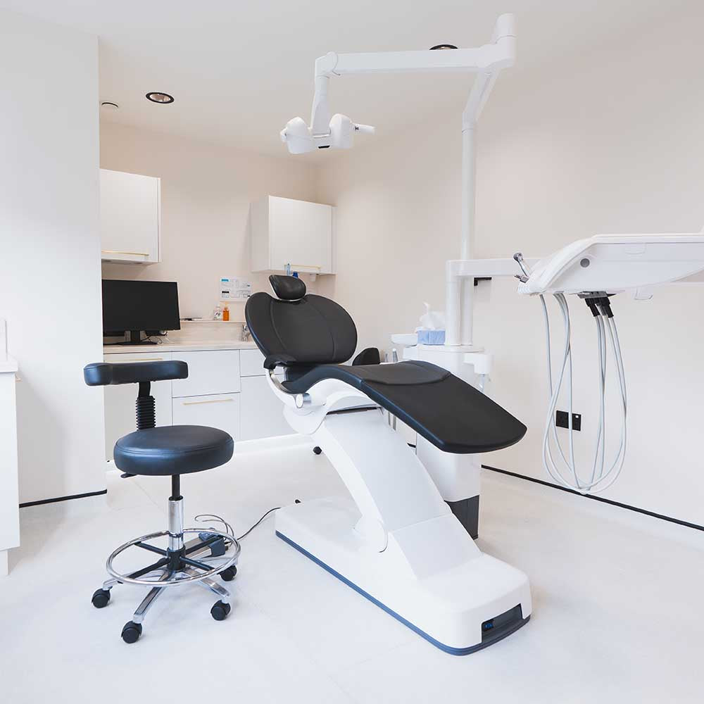 Dental examination chair in a clinical setting with medical equipment.