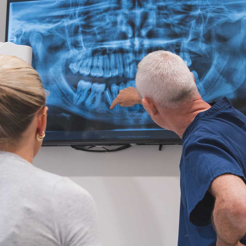 Two people examining a dental X-ray on a screen.