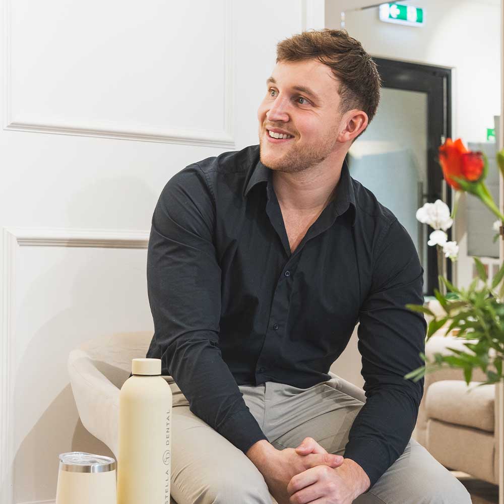 Man sitting in a modern interior setting with a bottle and glass.