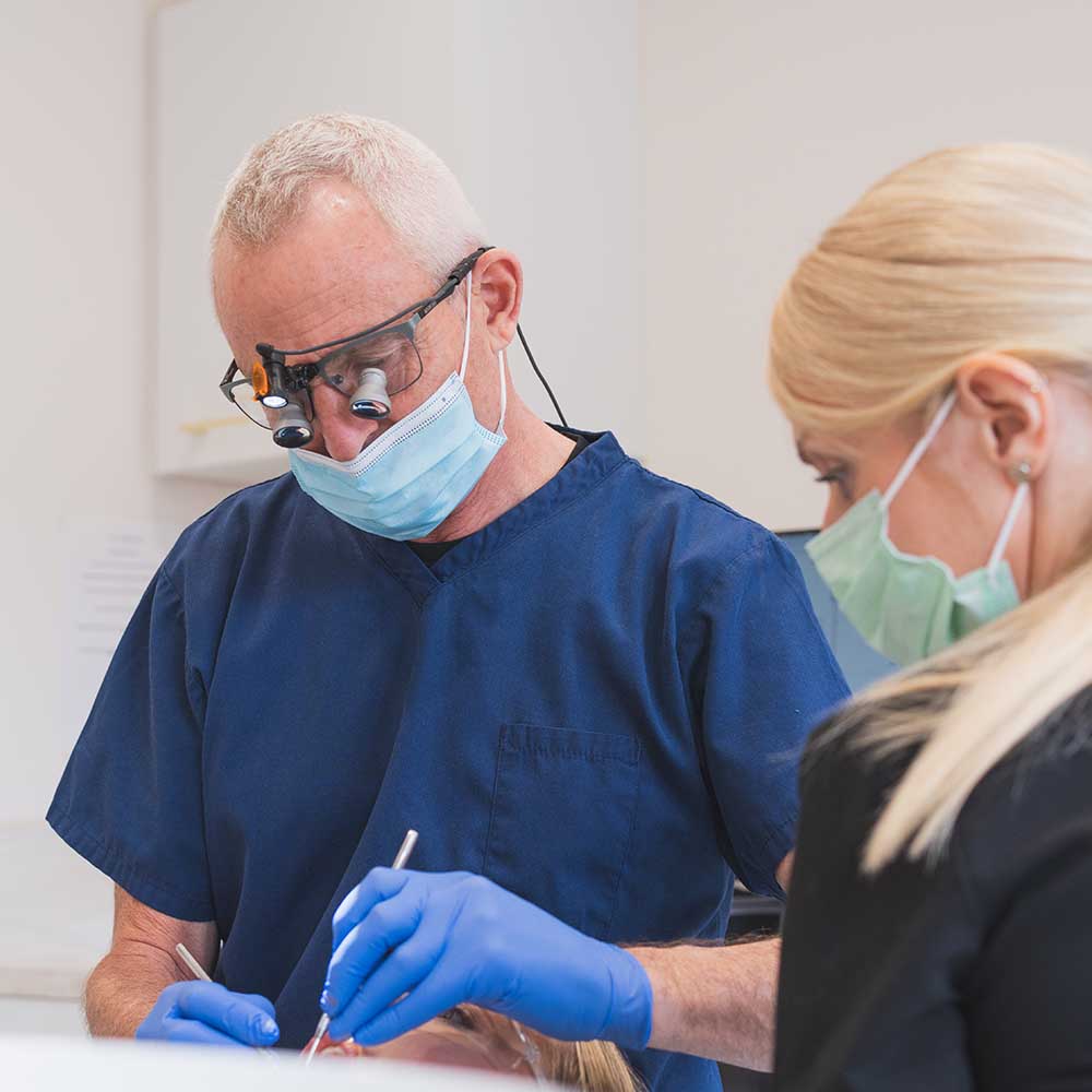 Dentist and dental assistant working on a patient in a clinical setting