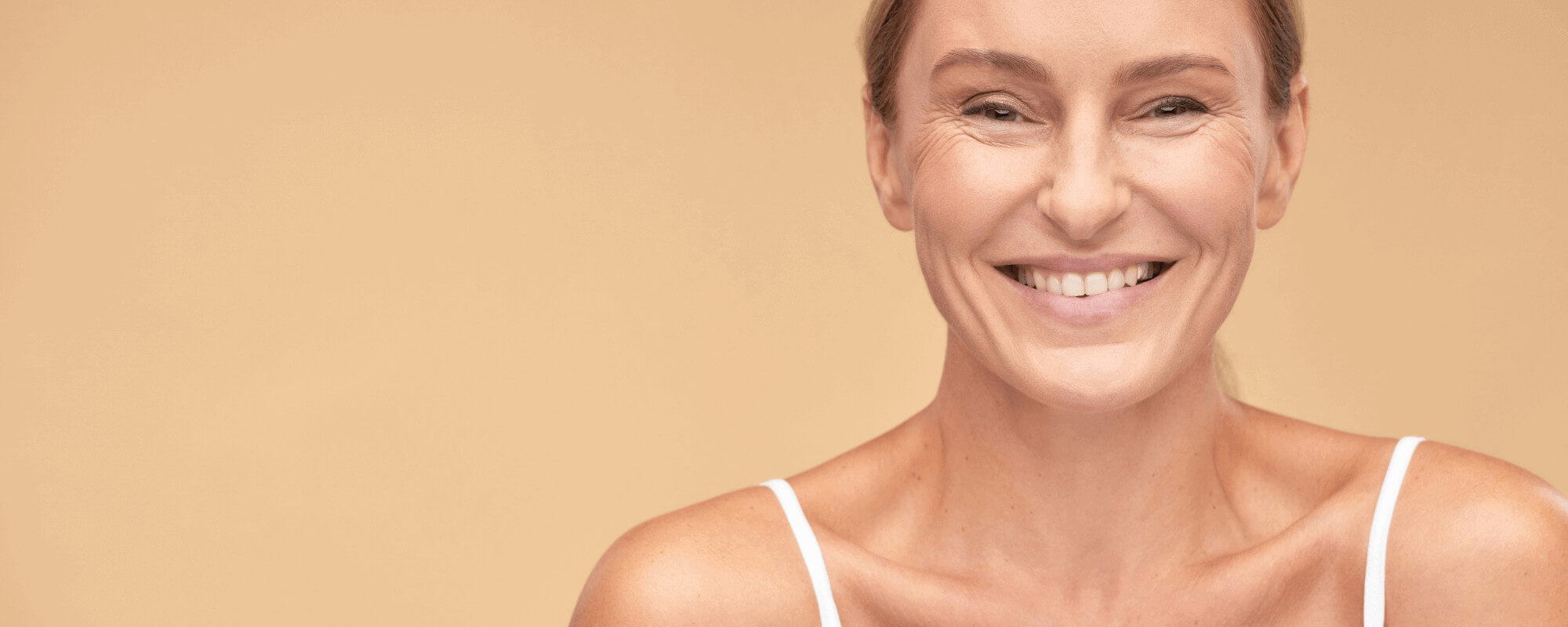 A woman with dental implants smiling towards the camera, showing her new white and straight smile.