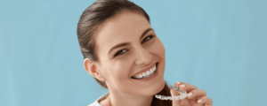 Woman holding her invisalign aligners, smiling at the camera.